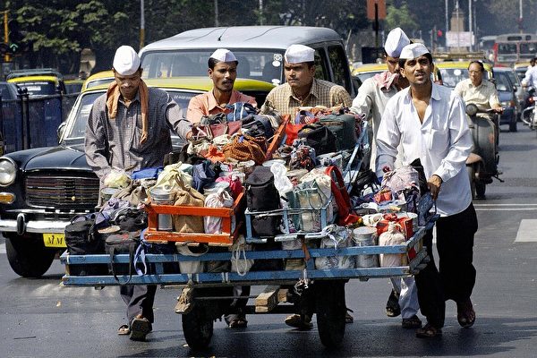 Mumbai, INDIA: (FILES) In this picture taken 04 February 2004, Indian dabbawallahs or tiffin carriers push their cart laden with food, on their way to make lunch time food deliveries, through the streets of Mumbai. Two of Mumbai's "lunch runners" who help supply tens of thousands of food boxes every day to workers in the crowded western Indian metropolis will teach management techniques to steel executives in India, a report said 03 February 2006. The two "dabbawallas" will run a three-day workshop for 2,000 workers of the Bhilai steel plant in central India, teaching "accuracy and precision", according to the Times of India. AFP PHOTO/Rob ELLIOTT/FILES (Photo credit should read ROB ELLIOTT/AFP/Getty Images)